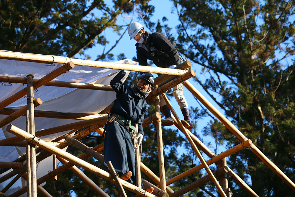御本殿足場組みの最終作業、とび職が背屋根を取り付けます